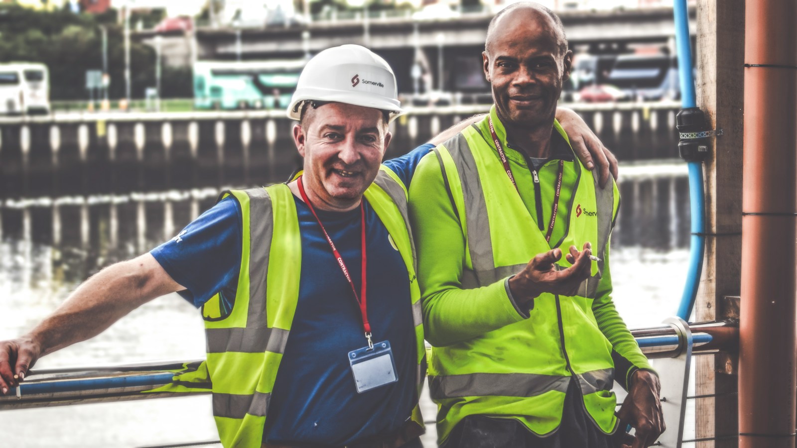 selective focus photography of two men standing side by side wearing green reflective vests equipped with workers compensation